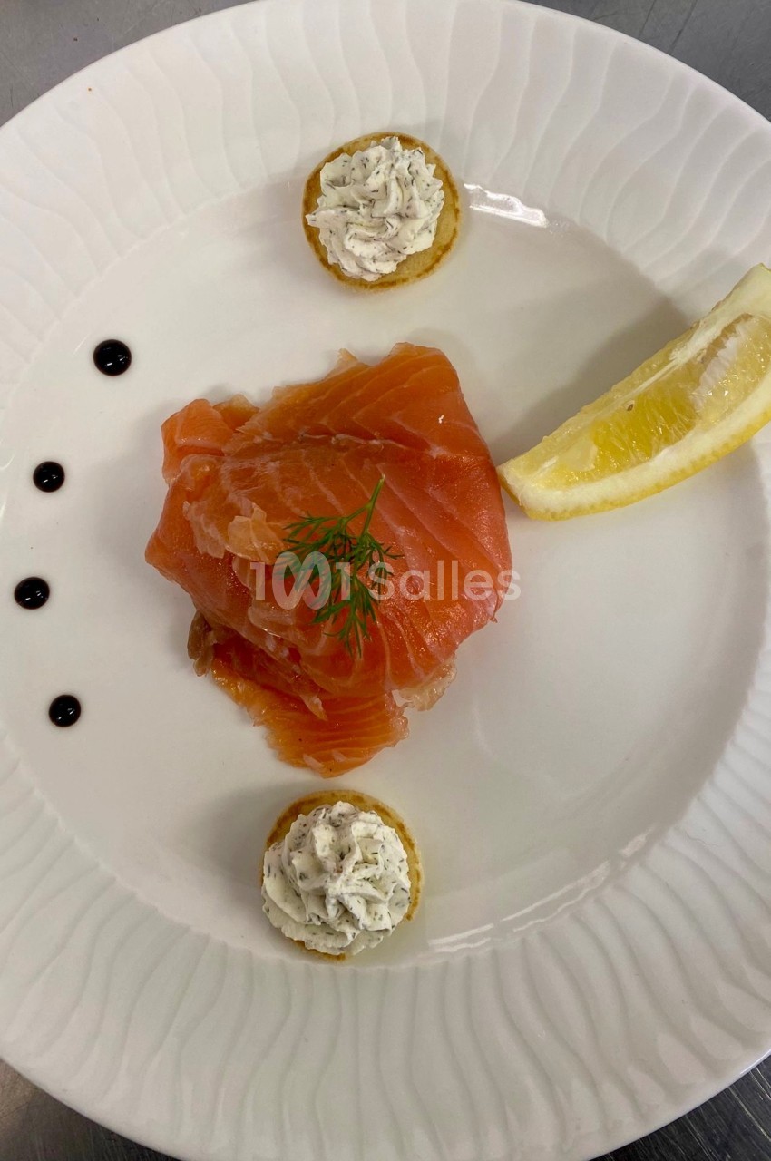 Assiette avec saumon fumé, citron, points de vinaigre balsamique et canapés garnis de fromage frais aux herbes.
