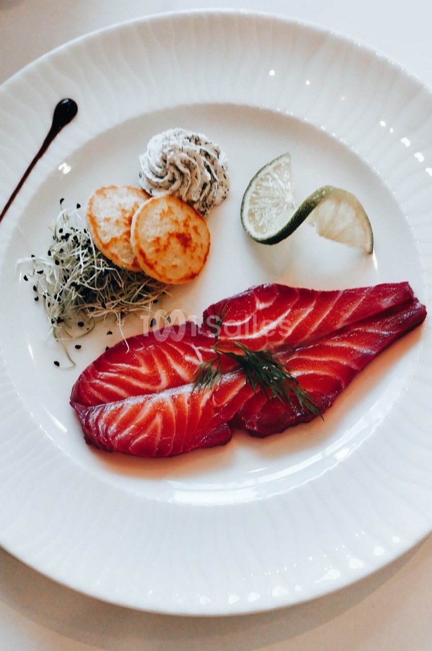 Assiette de saumon fumé avec herbes, rondelles de pommes de terre, mousse, germes et quartier de citron vert.