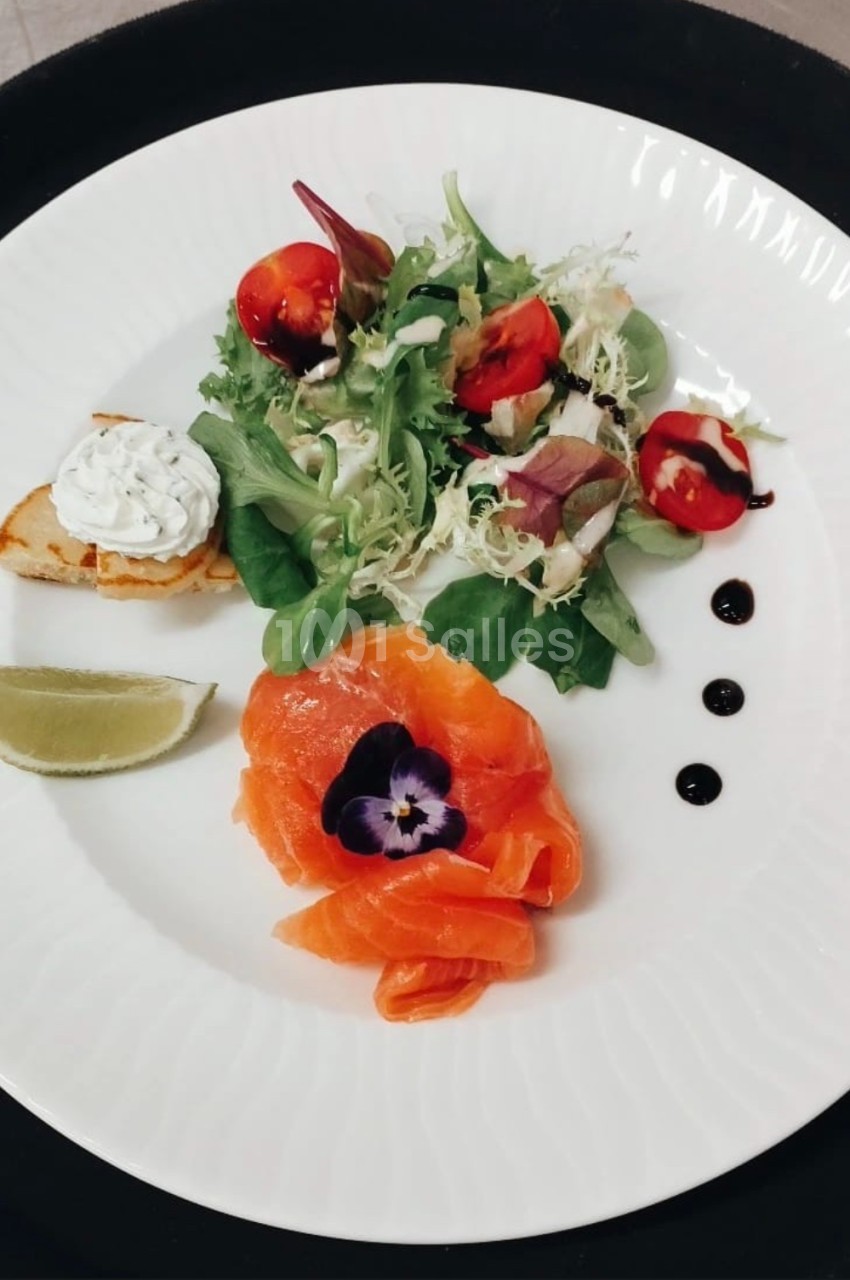 Assiette composée de saumon fumé, salade verte, toast garni, quartier de citron et décorations de sauce balsamique.