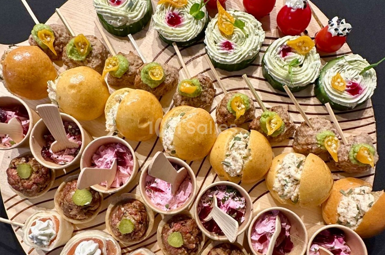 Plateau de bouchées apéritives variées comprenant mini-burgers, verrines, brochettes et amuse-bouches colorés.
