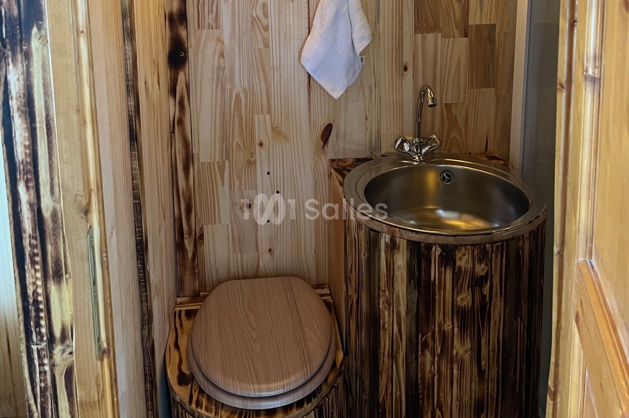 Toilettes en bois avec un lavabo en acier inoxydable intégré dans un meuble assorti, serviette suspendue au mur.