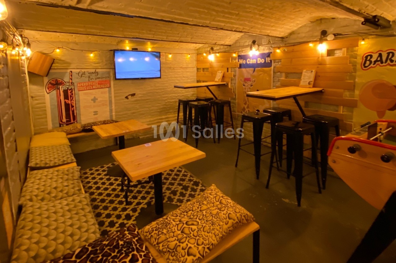 Salle voûtée avec tables en bois, chaises hautes, banquettes, affiches décoratives et éclairage chaleureux.