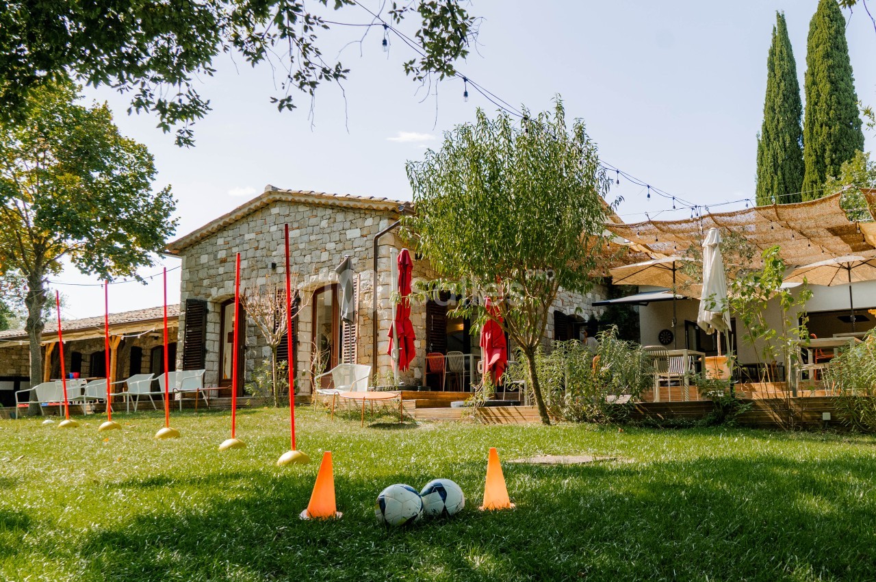 Propriété en pierre avec jeux de plein air en pelouse - piquets rouges, balles et cônes orange.