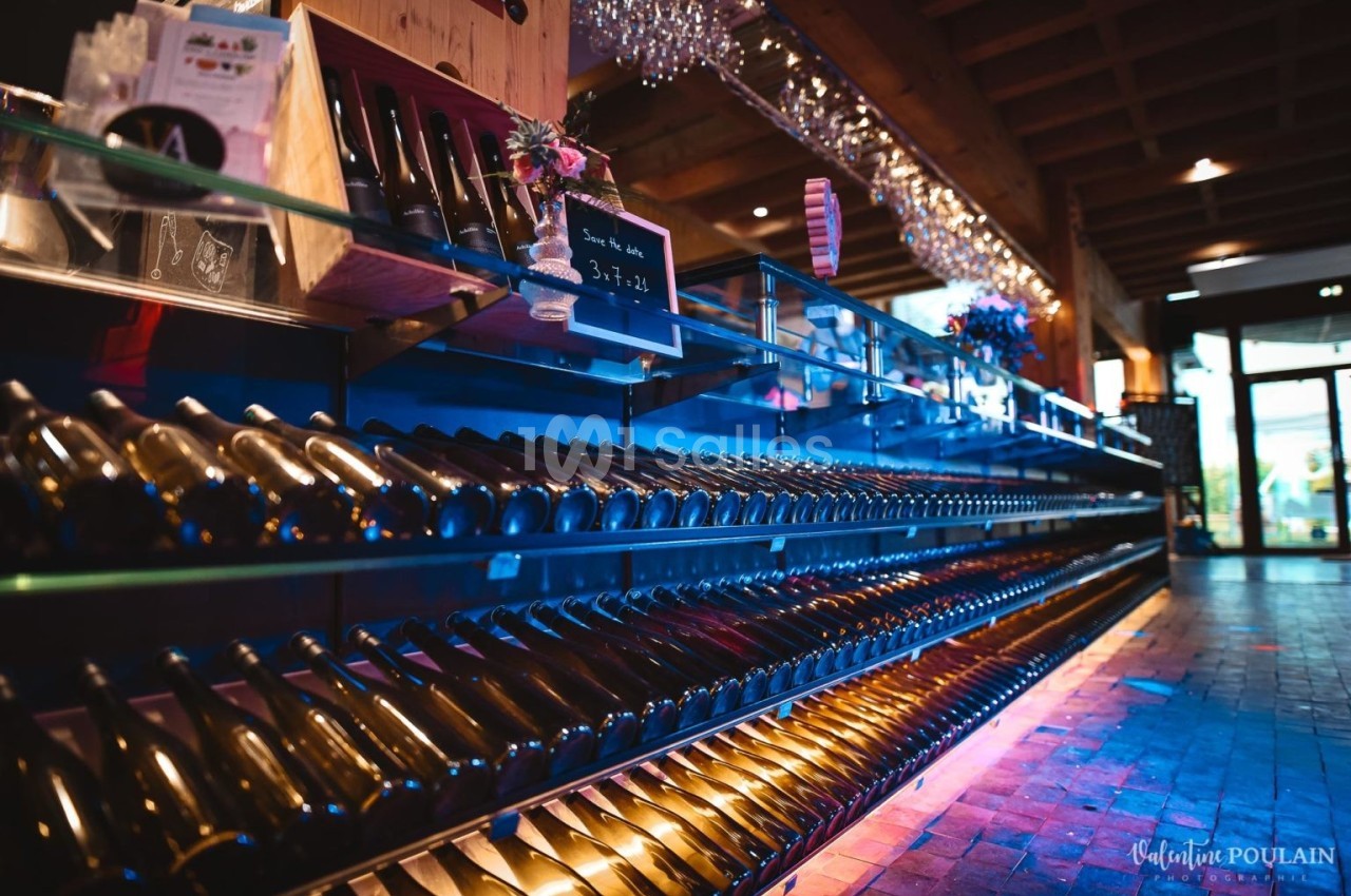 Rayonnage de bouteilles de vin alignées dans une cave ou un magasin, éclairage chaleureux et ambiance soignée.