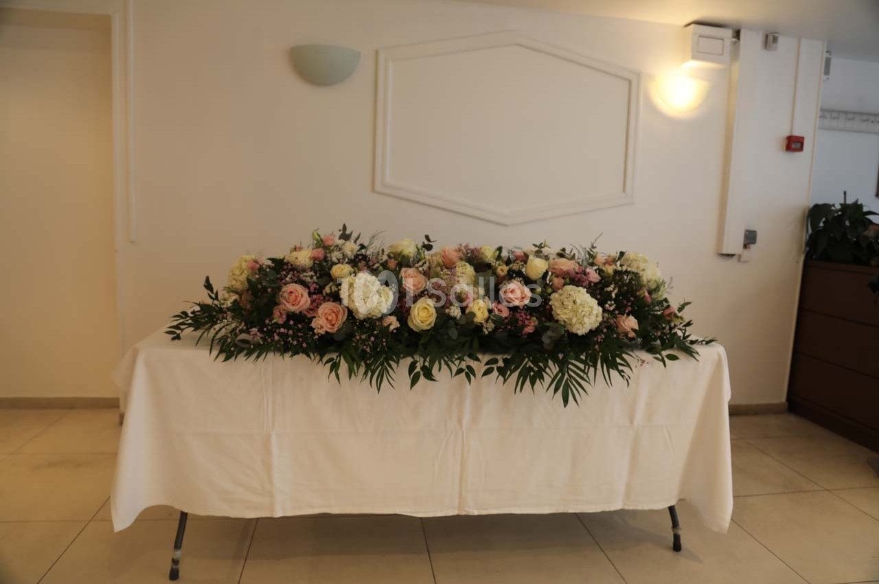 Arrangement floral coloré avec roses, hortensias et feuillage, posé sur une table recouverte d'une nappe blanche.