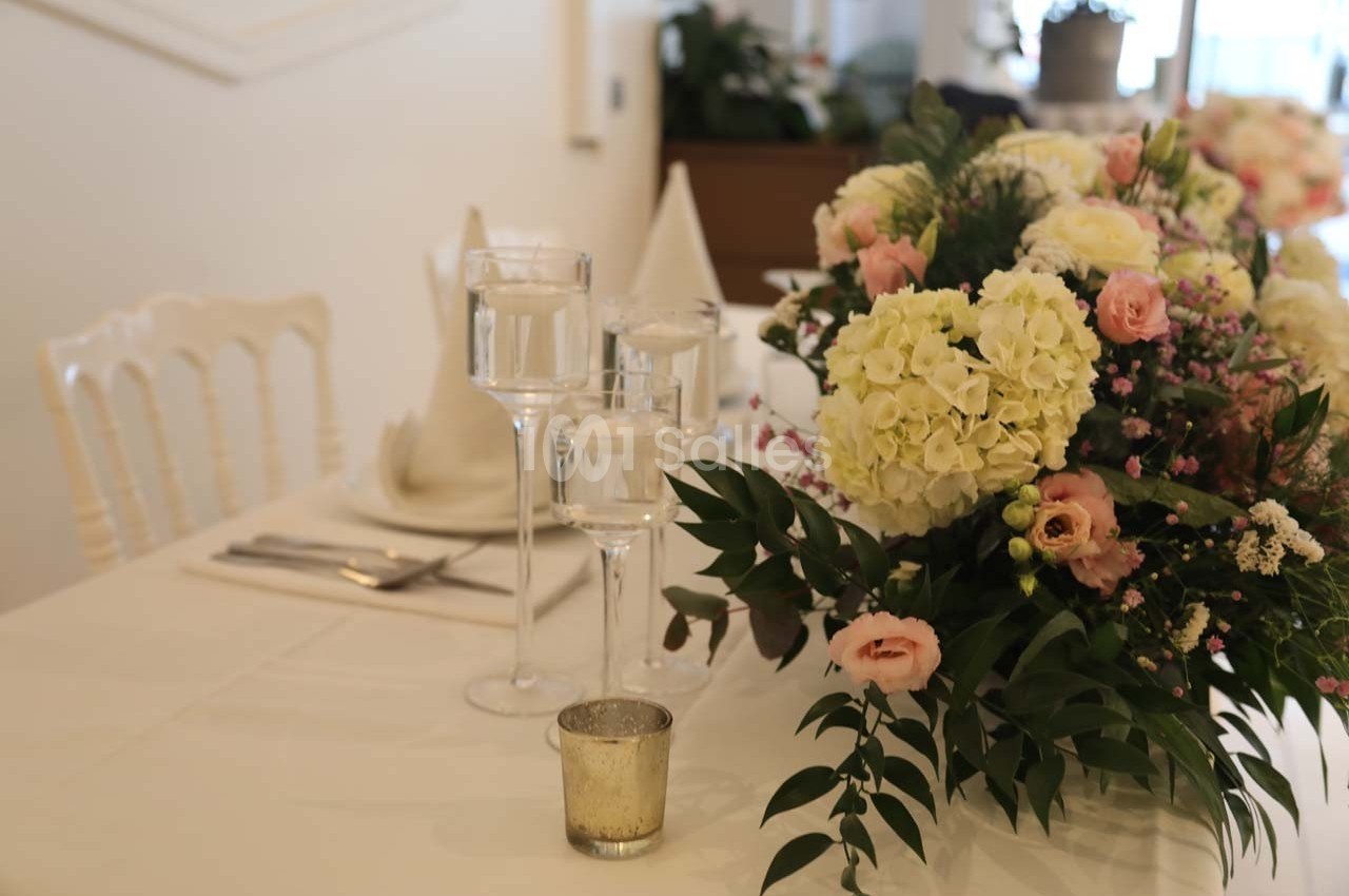 Table décorée avec un bouquet de fleurs pastel, des bougies et des serviettes pliées dans une ambiance élégante.