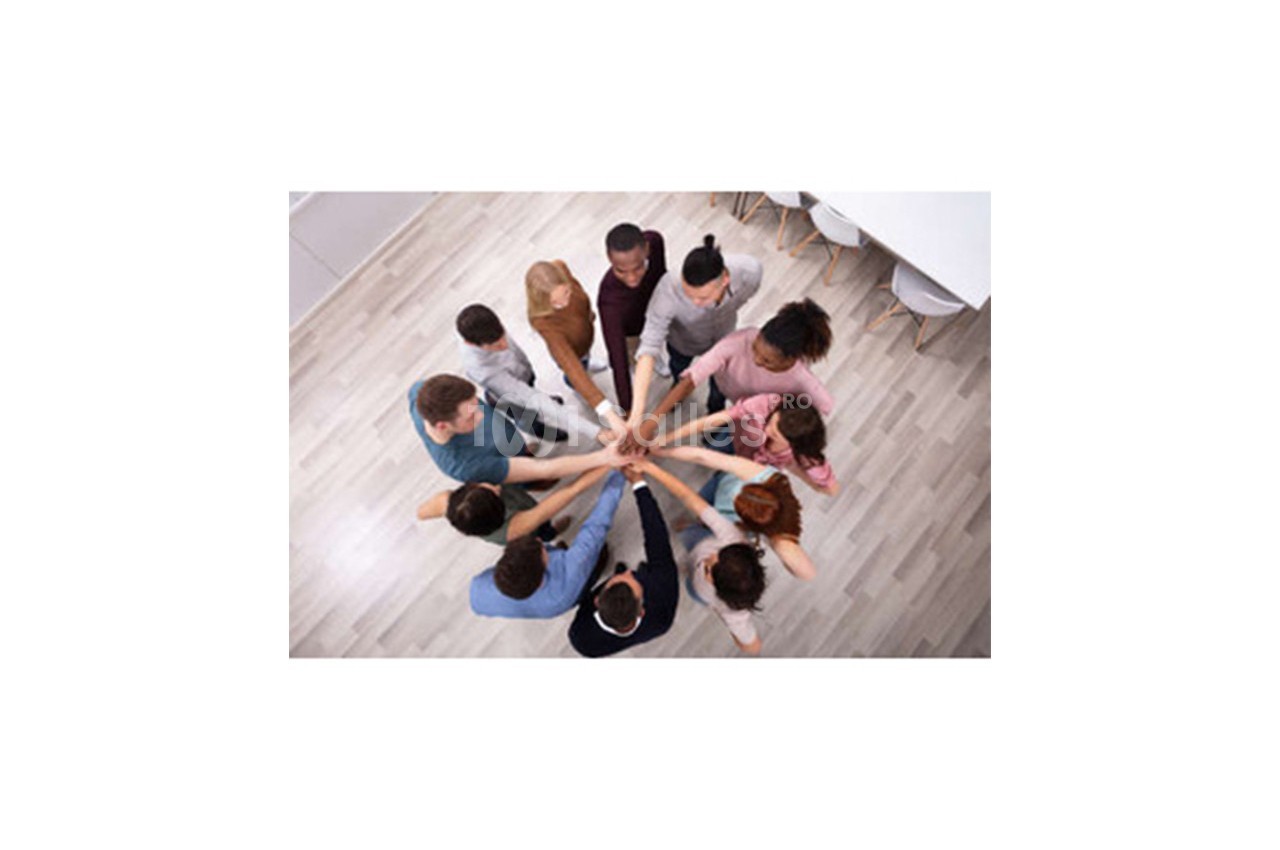 Des personnes debout en cercle joignent leurs mains au centre, symbolisant l'unité et la collaboration.