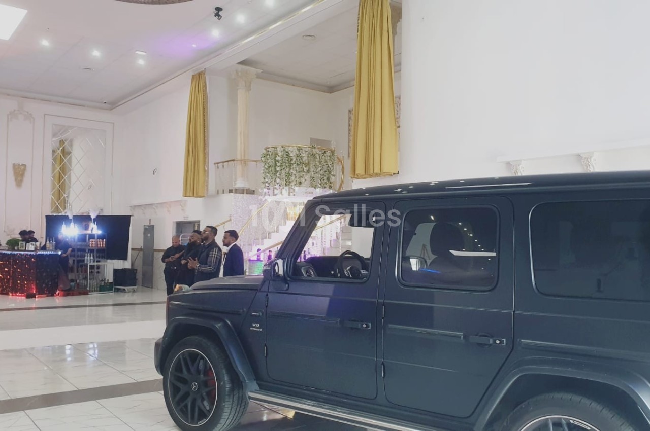Un SUV noir garé dans un hall spacieux avec des rideaux dorés et un décor lumineux en arrière-plan.
