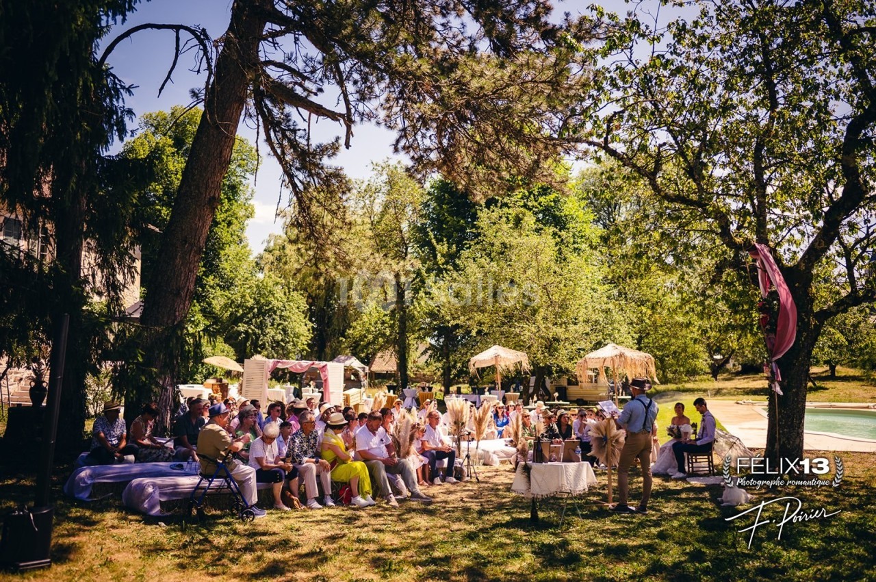 Groupe de personnes assises en extérieur lors d'un événement près d'une piscine, entourées d'arbres et de verdure.