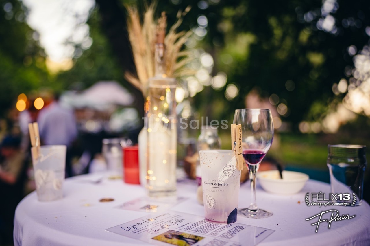 Table décorée en extérieur avec des verres, une bouteille et des éléments naturels comme des épis de blé.