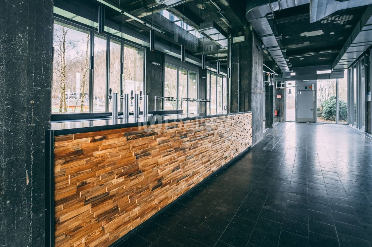 Comptoir en bois dans un espace moderne avec de grandes baies vitrées laissant entrer la lumière naturelle.