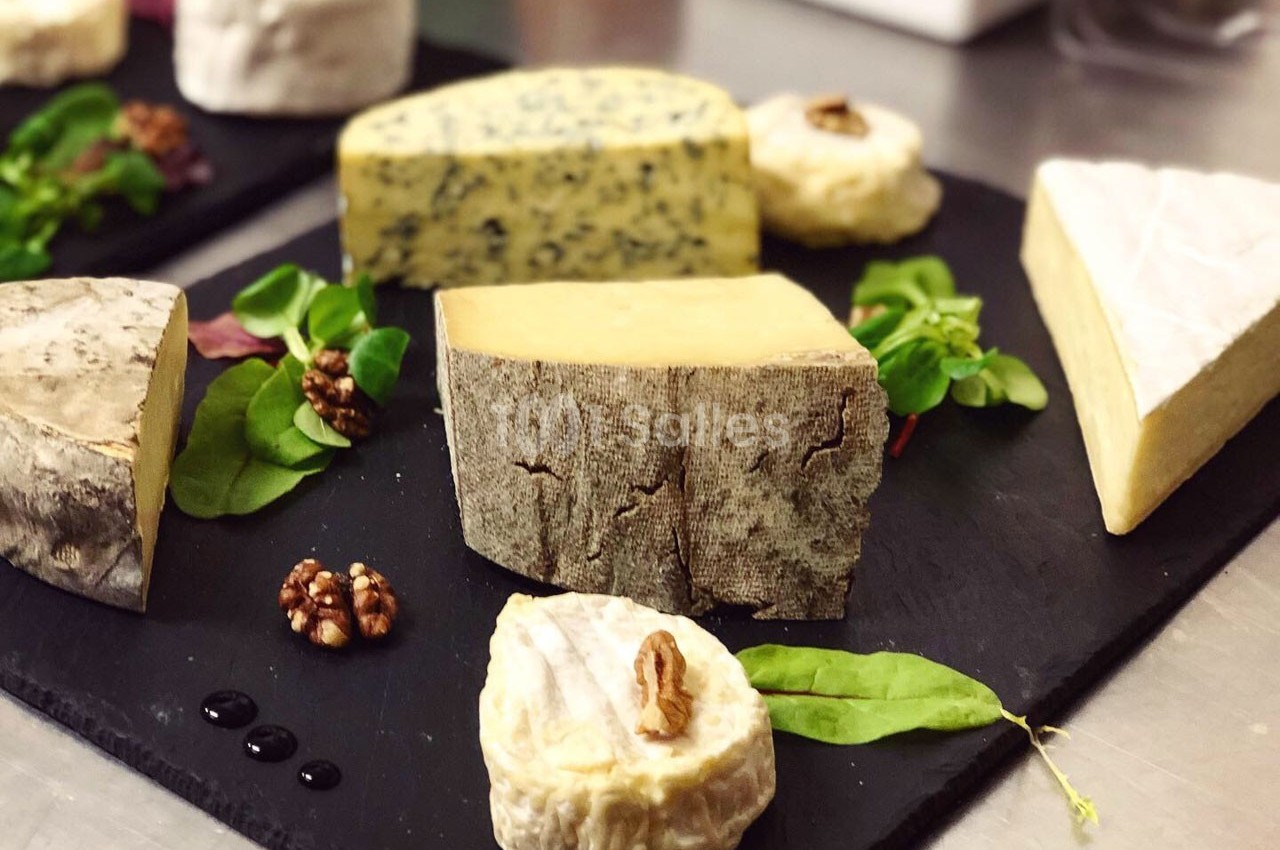 Assortiment de fromages variés disposés sur des ardoises avec noix et feuilles de salade en décoration.