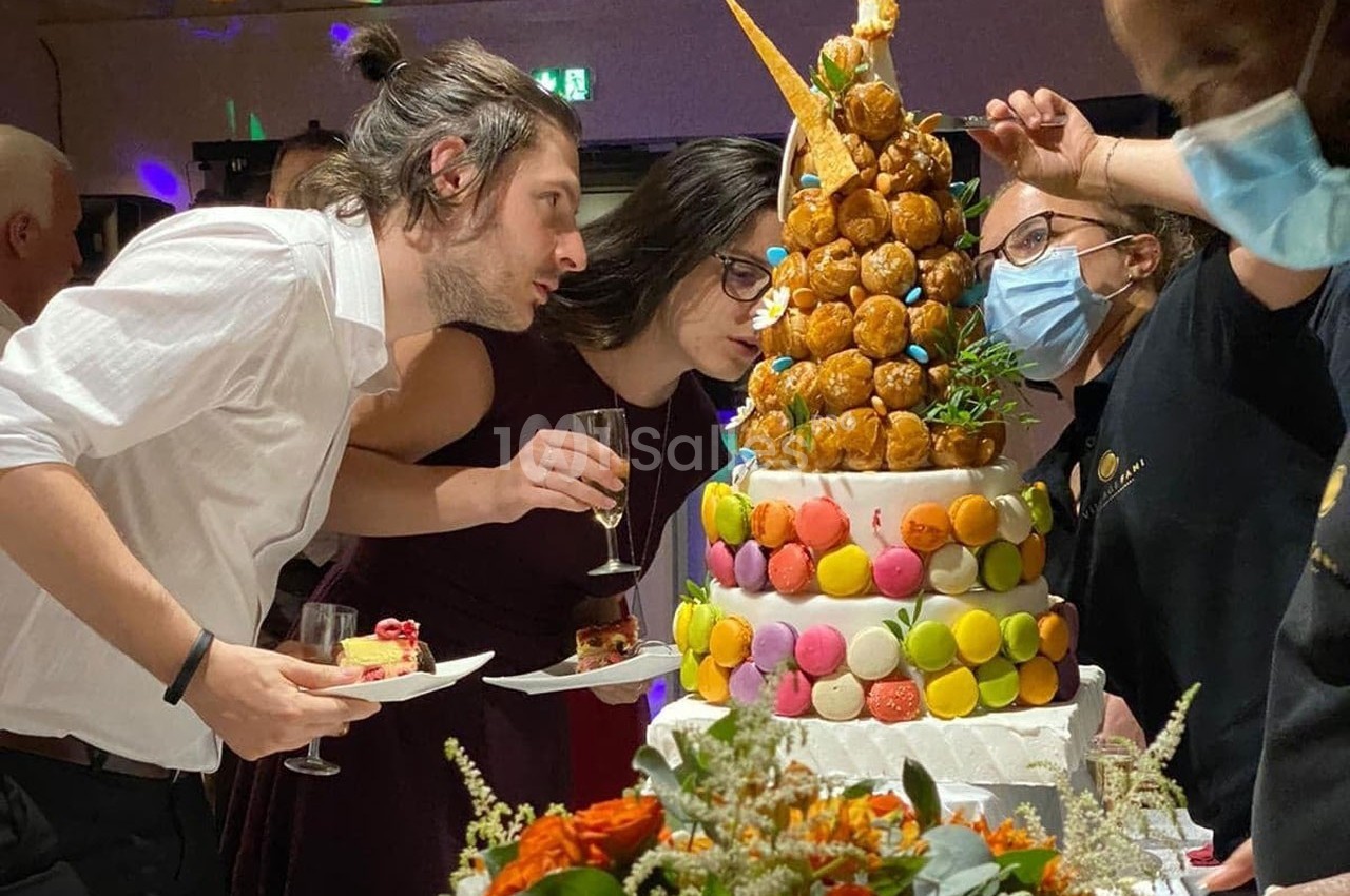 Des personnes observent une pièce montée décorée de macarons et de choux lors d'une réception festive.