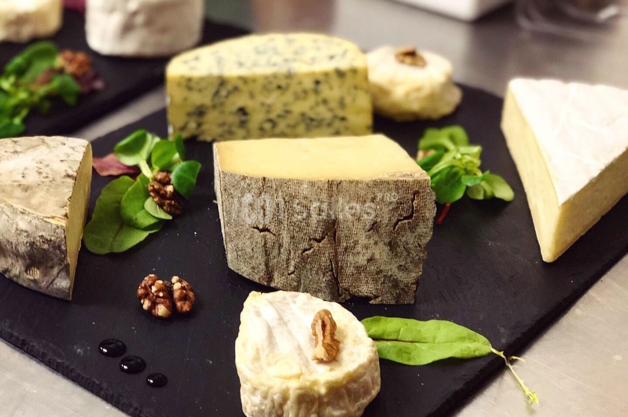 Assortiment de fromages variés disposés sur des ardoises avec noix et feuilles de salade en décoration.