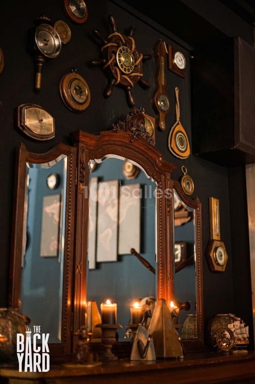 Miroir ancien entouré de décorations nautiques et d'objets vintage, avec des bougies allumées sur une étagère en bois.