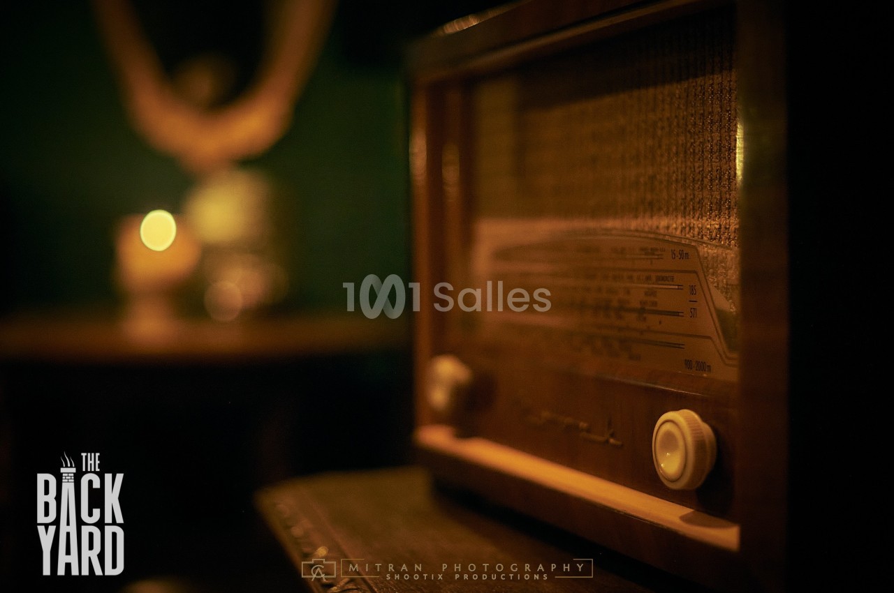 Radio vintage en bois posée sur une table dans une ambiance tamisée avec une lumière douce en arrière-plan.