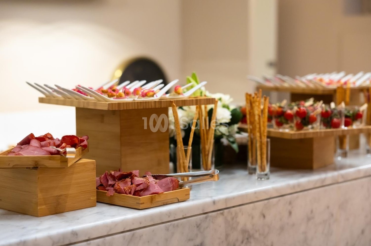 Plateau de charcuterie, brochettes et gressins disposés sur une table en marbre avec une présentation soignée.