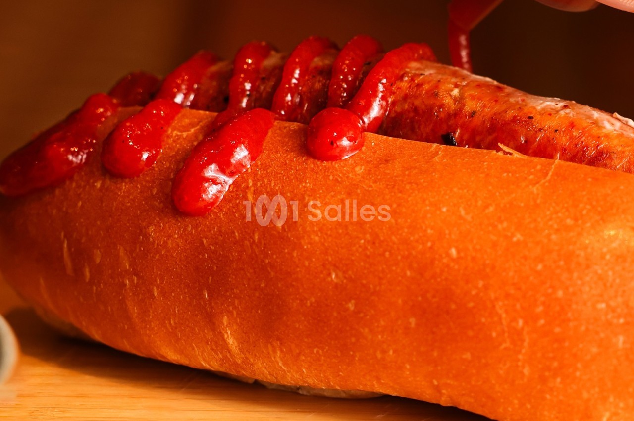 Saucisse grillée dans un pain moelleux, garnie de ketchup appliqué en zigzag.