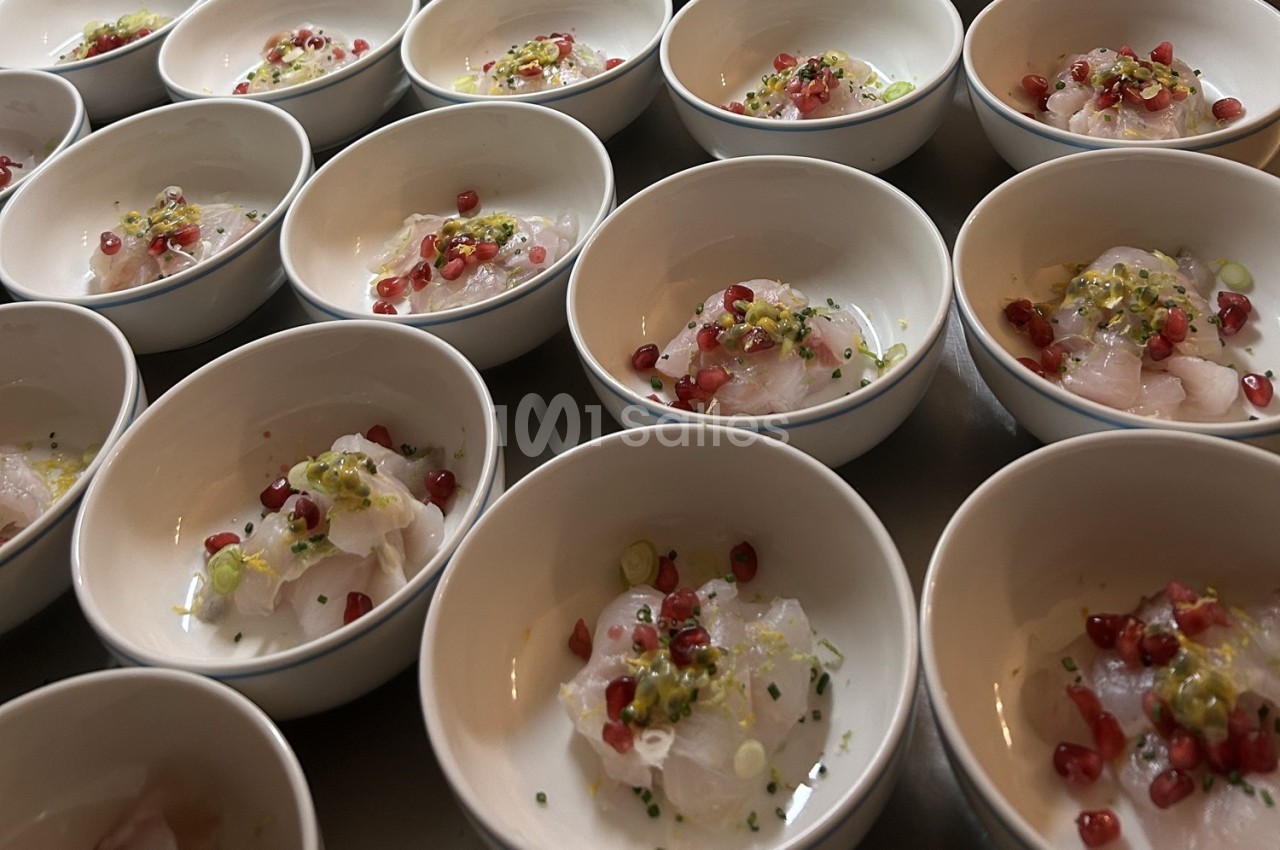 Petites assiettes contenant des portions de ceviche garnies de grenade, herbes et sauce.