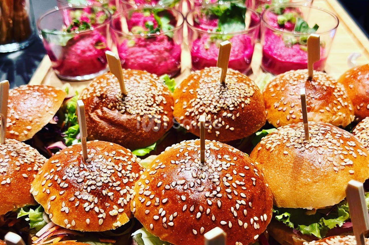 Mini-burgers garnis de graines de sésame accompagnés de verrines de mousse rose décorées de persil.