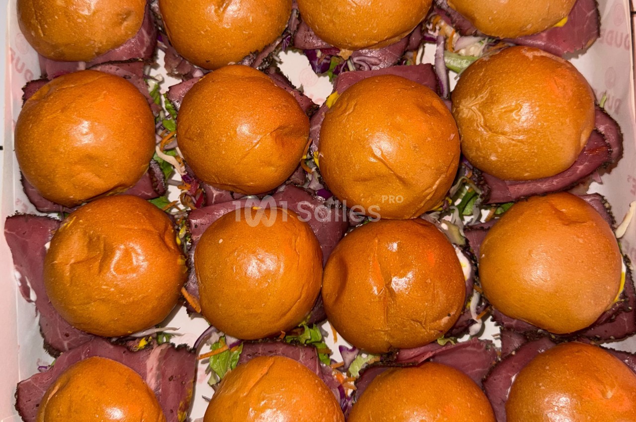 Plateau de mini-burgers au pain brioché, garnis de viande et de légumes colorés.