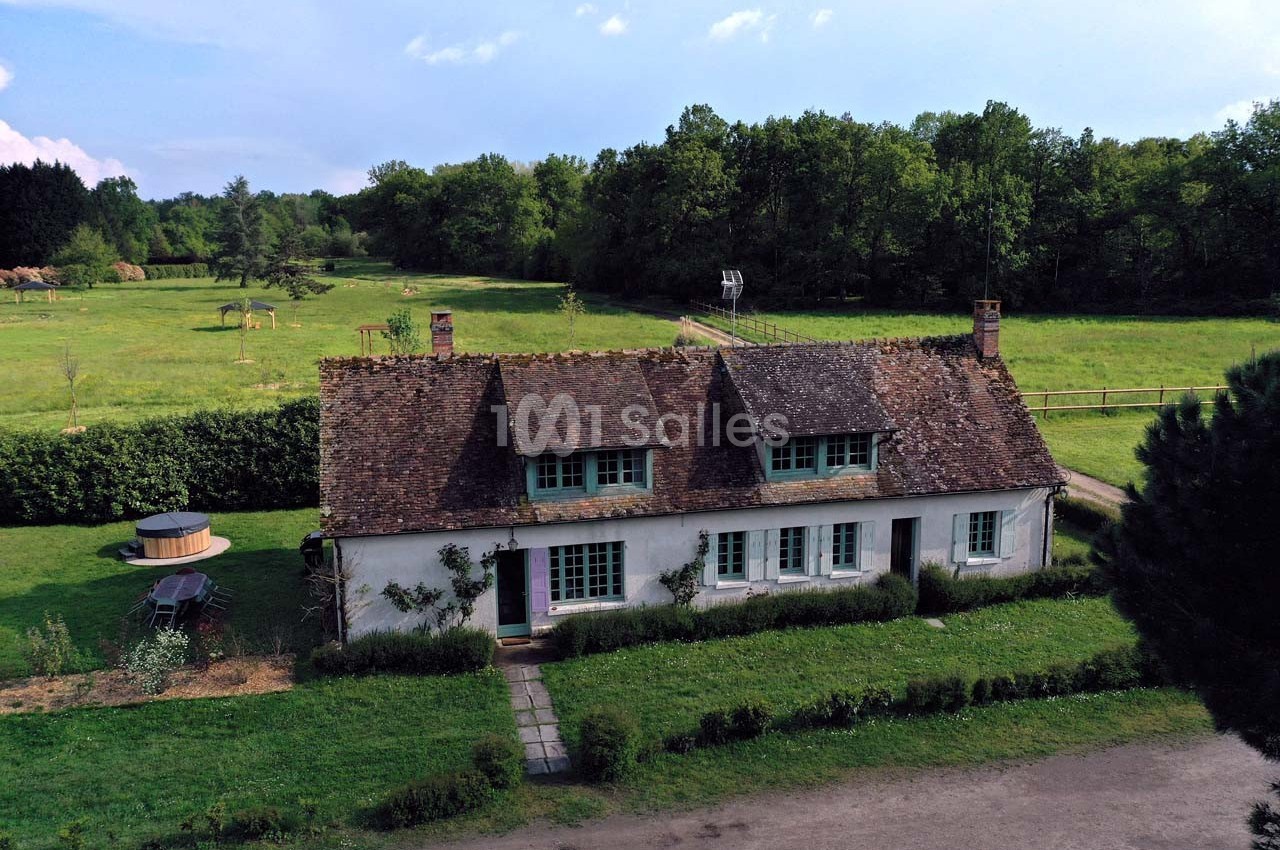 Maison traditionnelle avec toit en tuiles, entourée de verdure, située dans un cadre champêtre avec un jacuzzi extérieur.