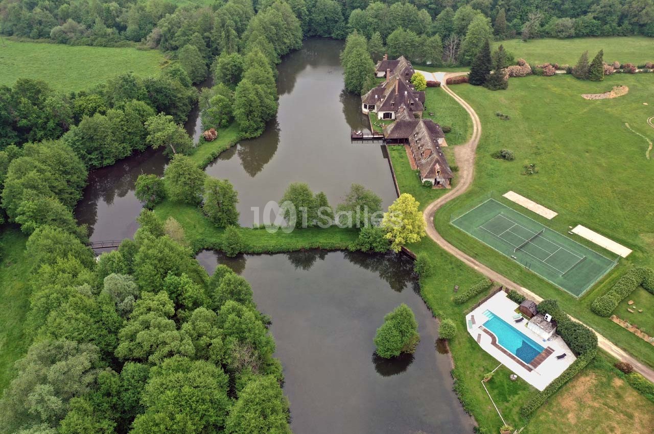 Vue aérienne d'un domaine avec étang, bâtiments anciens, piscine, terrains de tennis et espaces verts environnants.