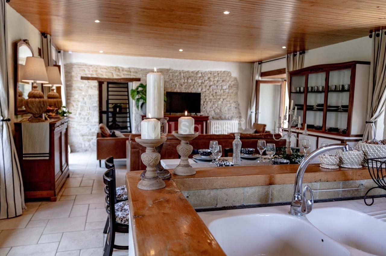 Vue d'une cuisine ouverte sur un salon avec murs en pierre, plafond en bois et décoration chaleureuse.