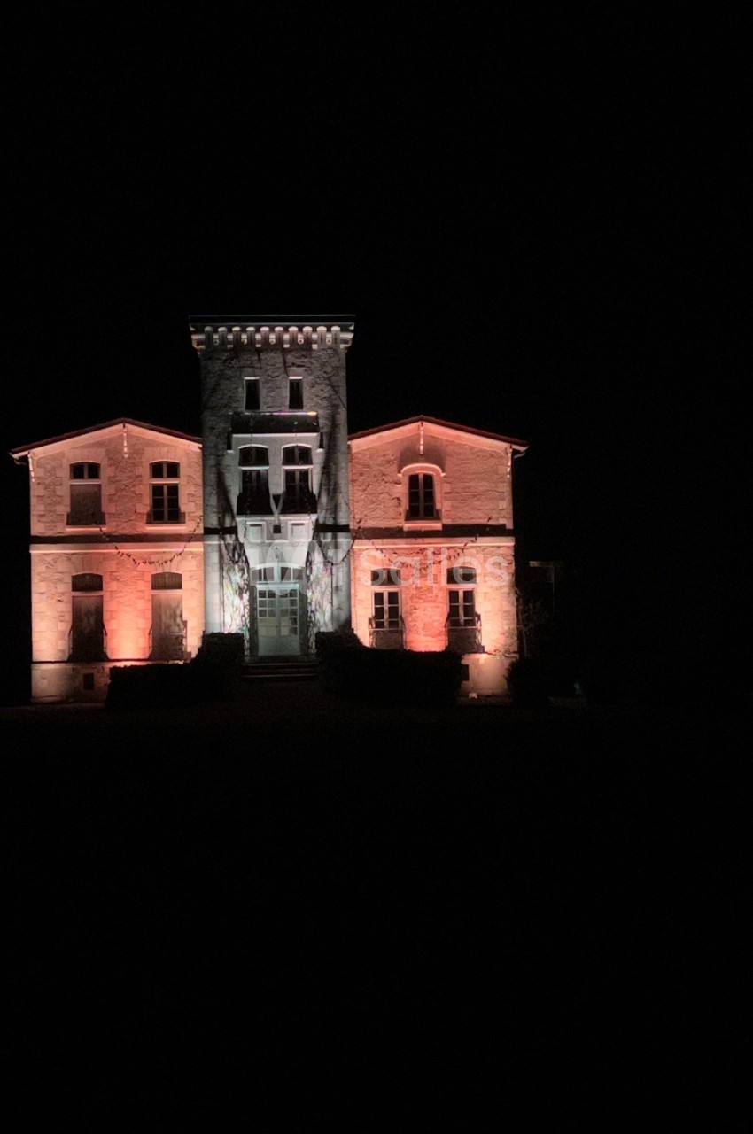 Façade d'un bâtiment en pierre éclairée par des lumières rouges et blanches, de nuit.