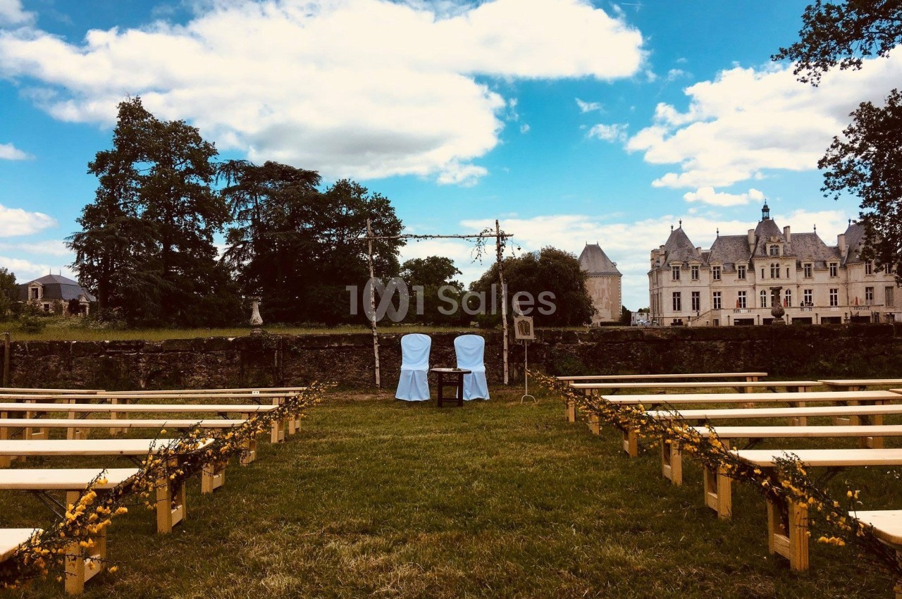 Deux chaises décorées face à une allée bordée de bancs en bois, dans un jardin avec un château en arrière-plan.