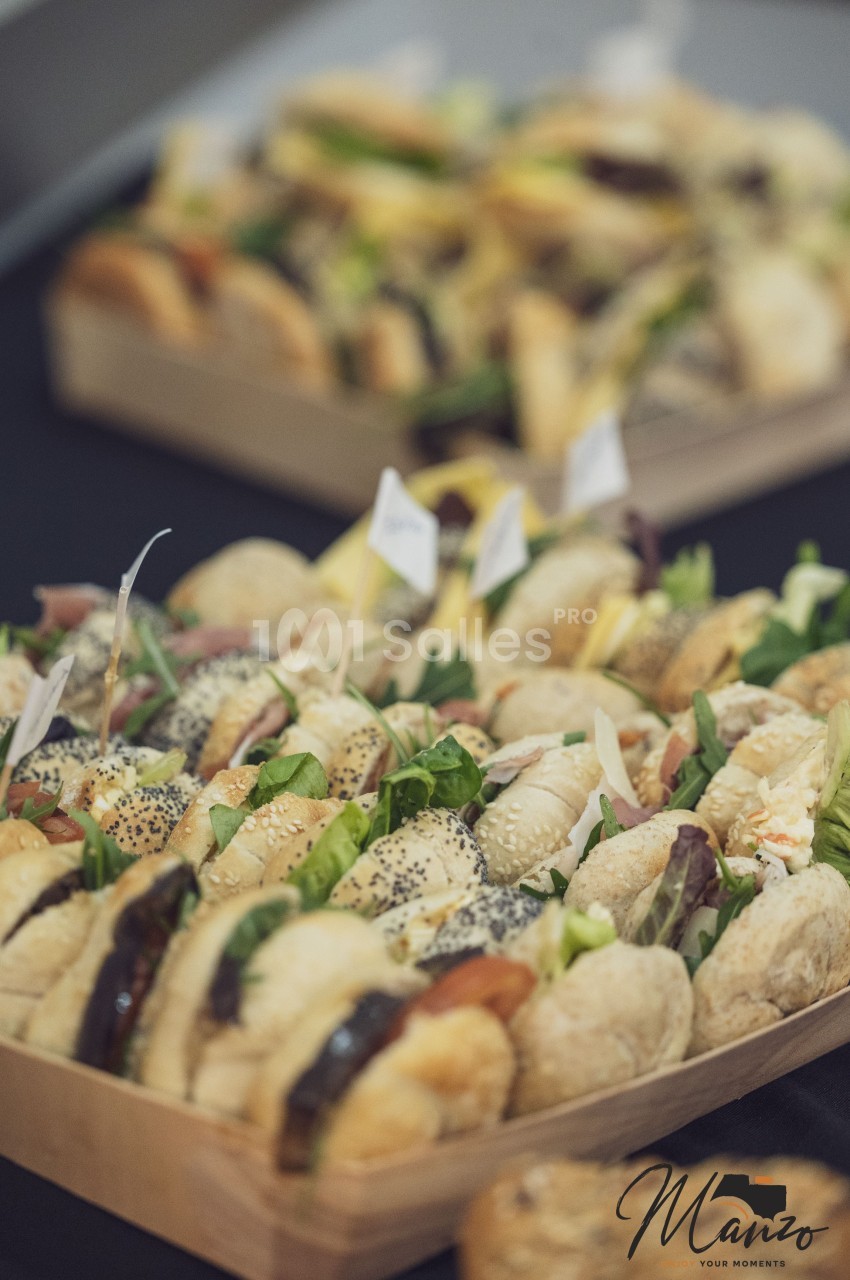 Plateaux de mini-sandwichs variés garnis de légumes, charcuteries et fromages, présentés sur une table noire.