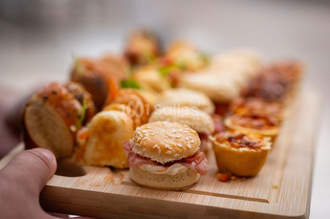 Plateau en bois garni de mini-sandwichs, bouchées salées et amuse-bouches variés.