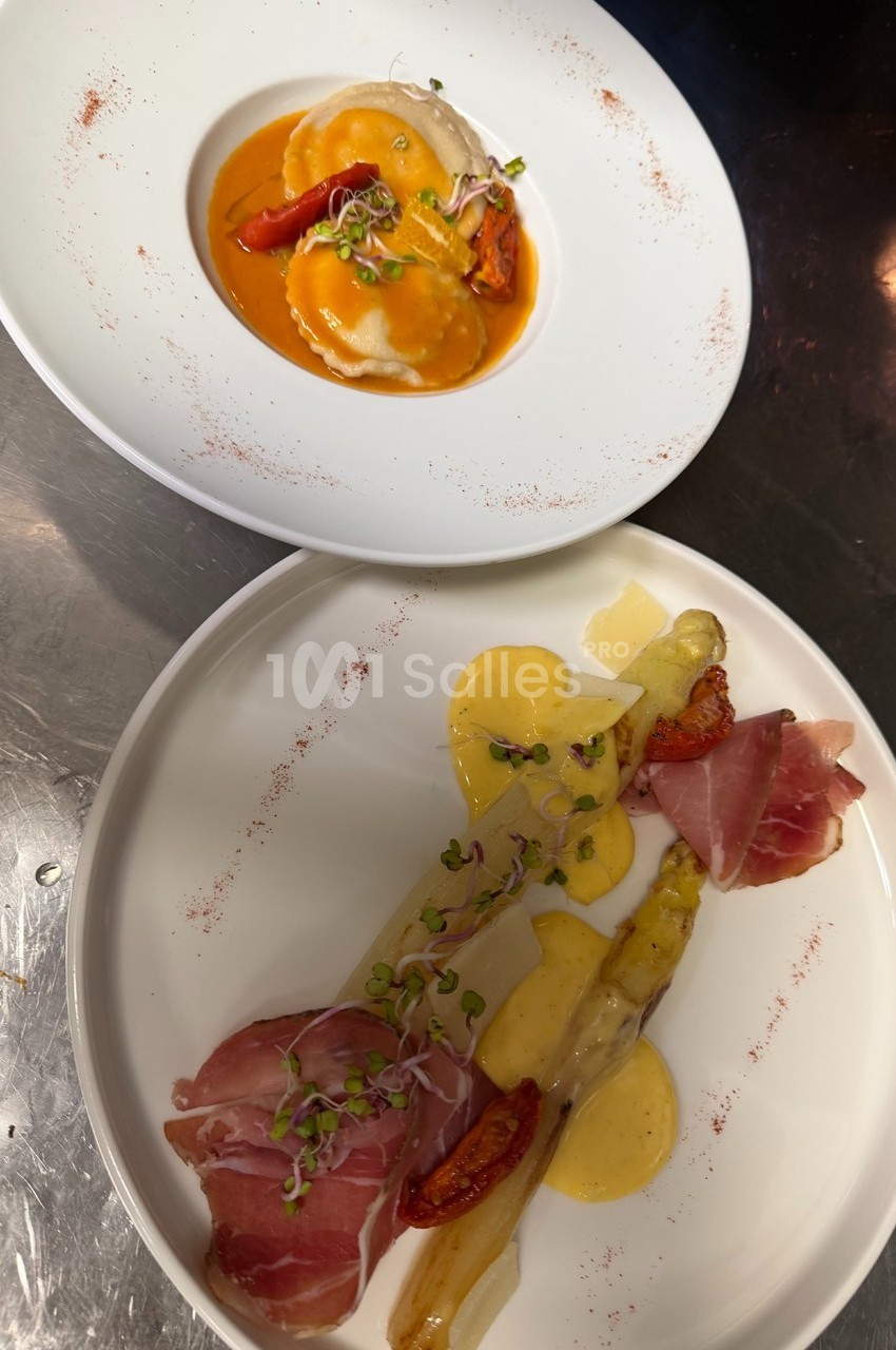 Assiette de ravioles en sauce et assiette d'asperges avec jambon cru, tomates confites et sauce hollandaise.