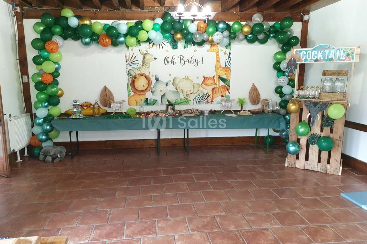 Décoration de fête avec ballons verts et animaux, table garnie de snacks et stand de boissons en bois.