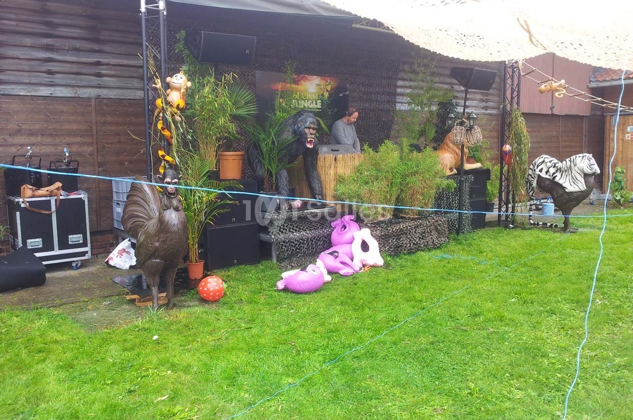 Un stand décoré sur le thème de la jungle avec des statues d'animaux et un DJ en arrière-plan.