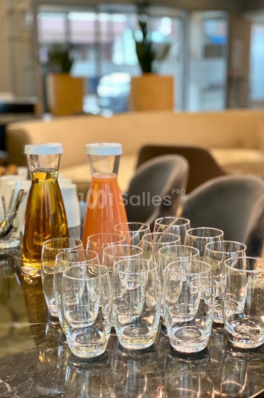 Carafes de jus et d'eau avec des verres vides disposés sur une table dans un espace intérieur lumineux.
