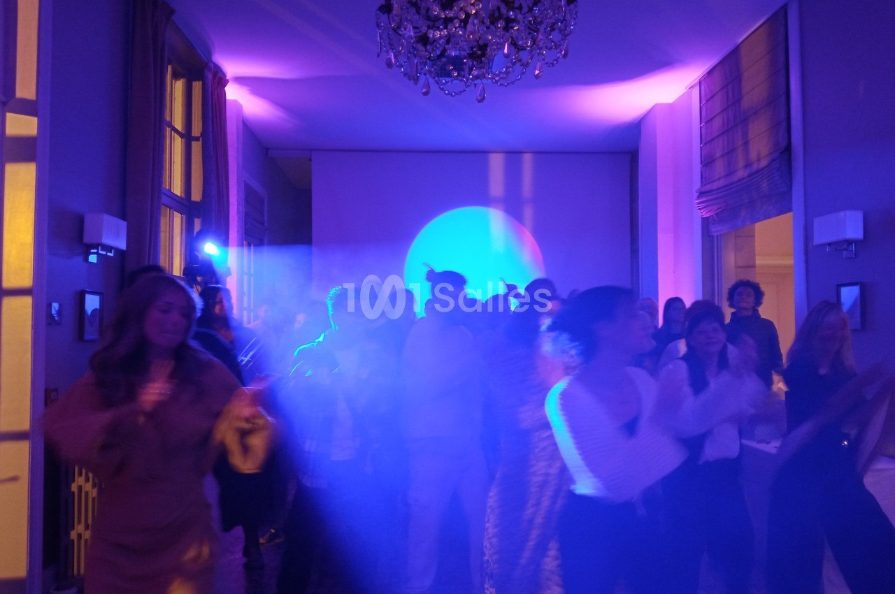 Groupe de personnes dansant dans une salle éclairée par des lumières colorées, ambiance festive.