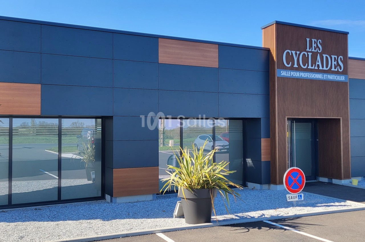 Façade d'un bâtiment commercial moderne avec enseigne ’Les Cyclades’, grandes vitrines et plantes en pots.