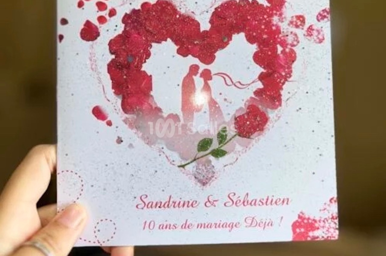 Carte blanche avec un cœur rouge formé de pétales, deux silhouettes au centre et texte célébrant 10 ans de mariage.