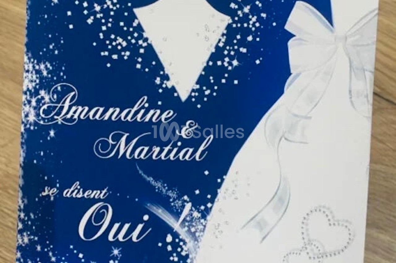 Carte de mariage bleue et blanche avec nœud papillon, rubans, cœurs et texte ’Amandine & Martial se disent Oui’.