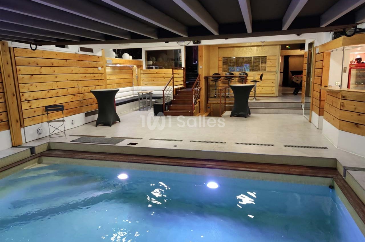 Espace intérieur avec piscine éclairée, murs en bois, mezzanine et mobilier moderne.