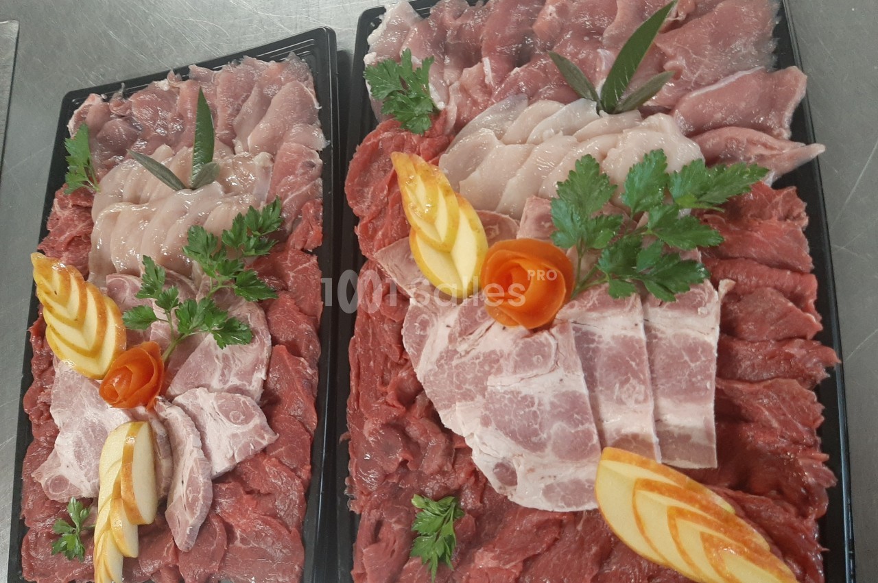 Plateaux de viande variée finement tranchée, décorés de persil, de roses en carotte et de tranches de pomme.