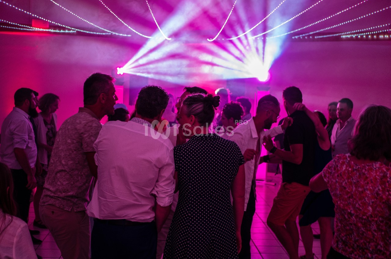 Groupe de personnes dansant sous des lumières colorées dans une salle sombre.
