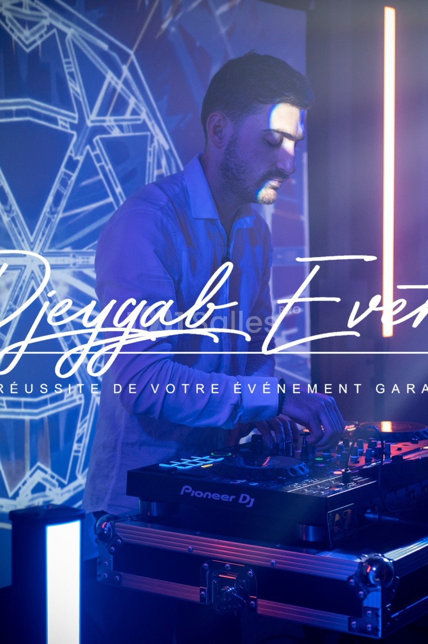 Un DJ mixant sur une table de mixage, éclairé par des lumières colorées et un décor lumineux en arrière-plan.