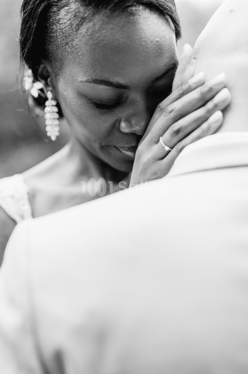 Femme émue posant sa main sur la tête d'un homme, capturée en noir et blanc dans un moment intime.