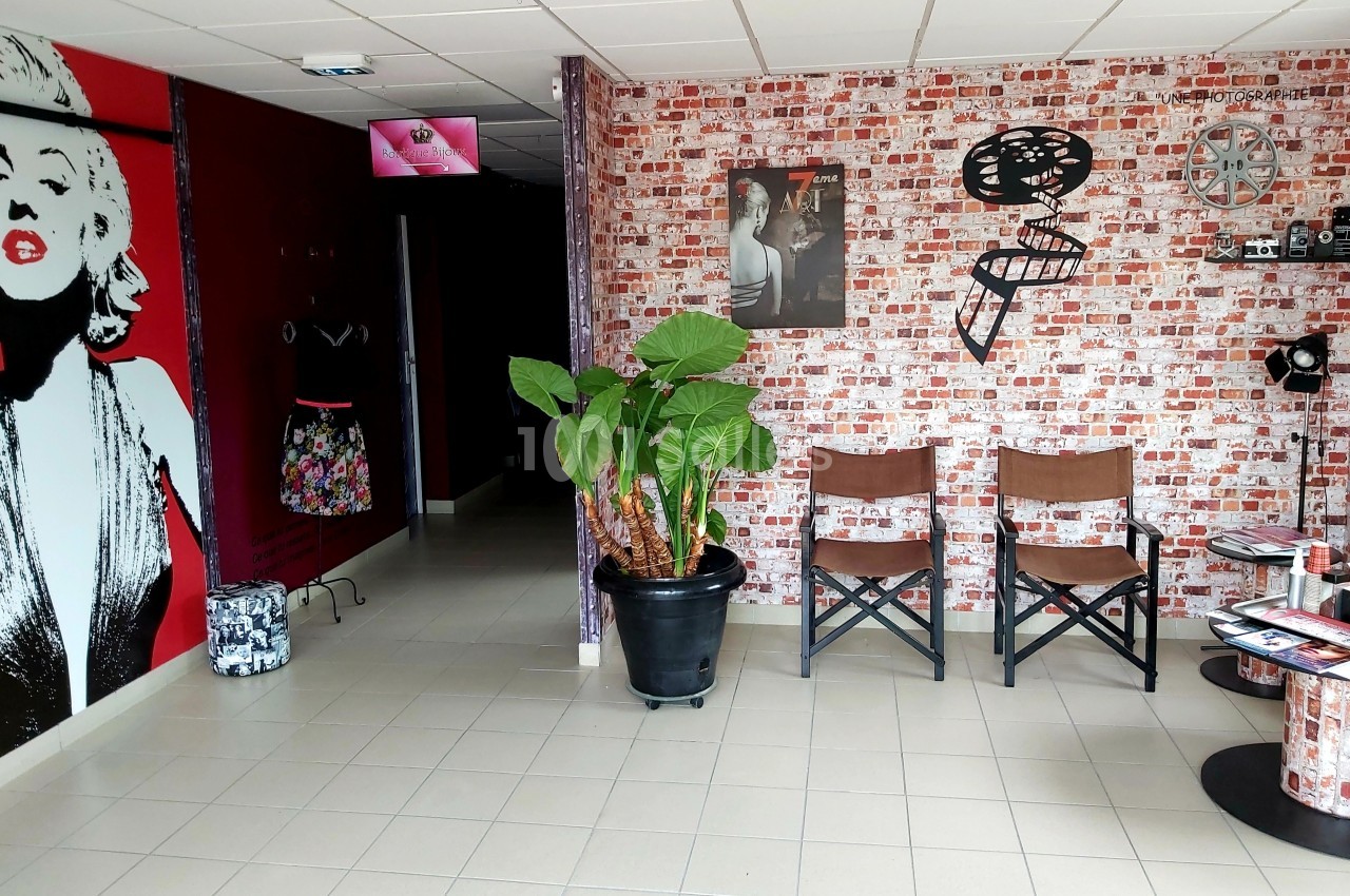 Mur décoré de motifs cinéma, plante en pot, deux chaises en bois et éléments de décoration rétro.