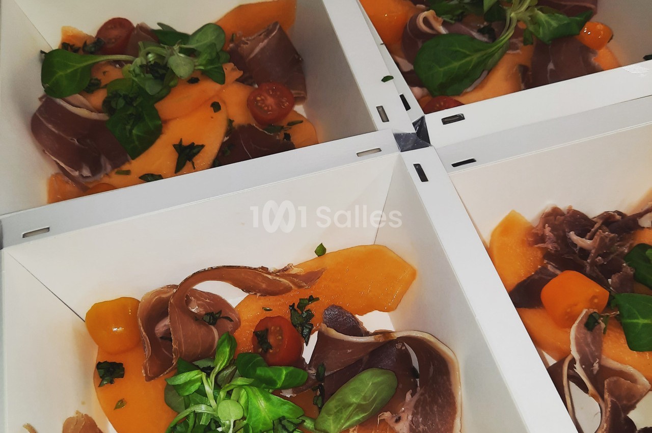 Assiettes en carton contenant du melon, du jambon cru, des tomates cerises et de la roquette fraîche.