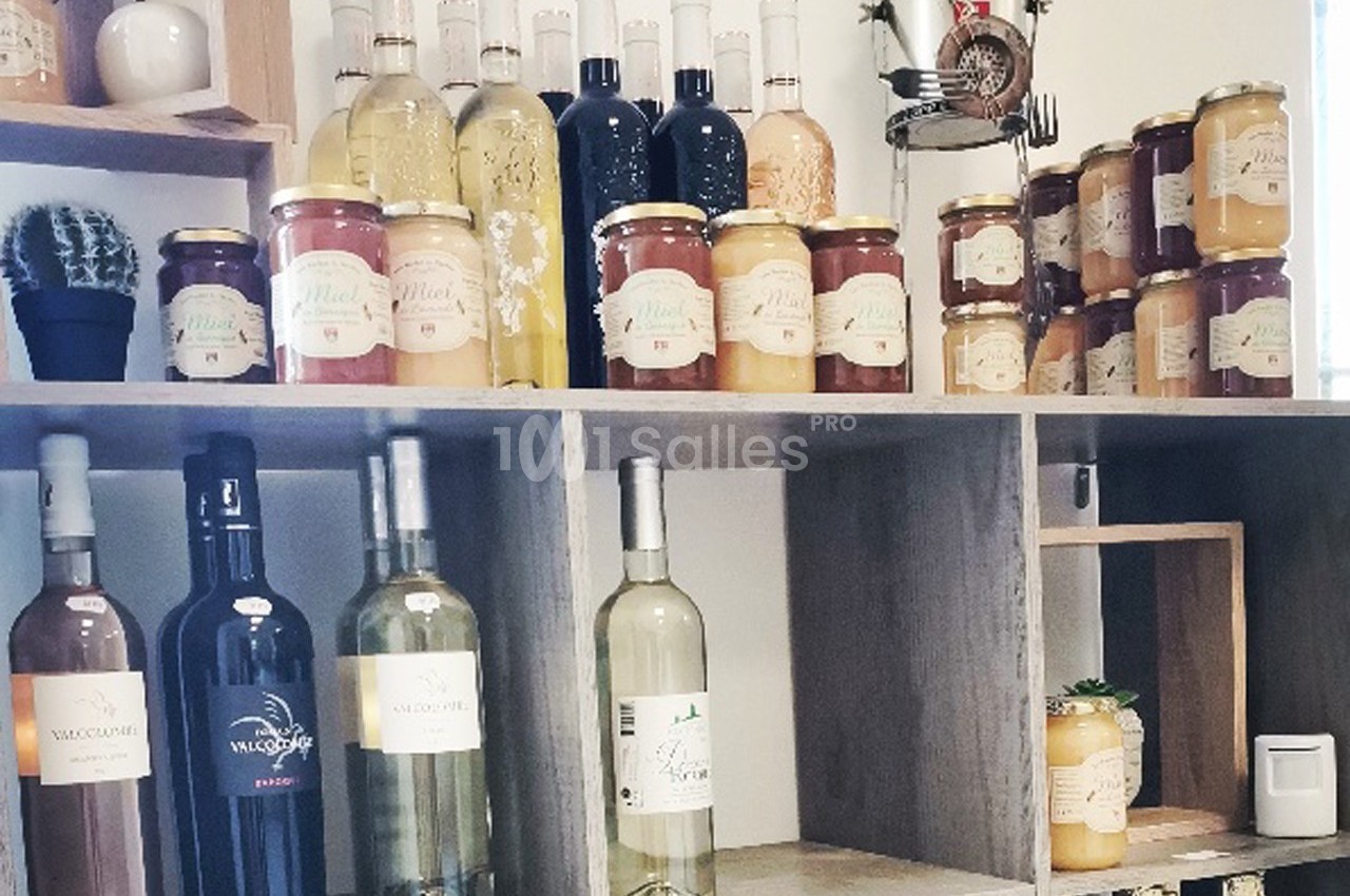 Étagères en bois avec bouteilles de vin, pots de miel et confitures, et un cactus décoratif.