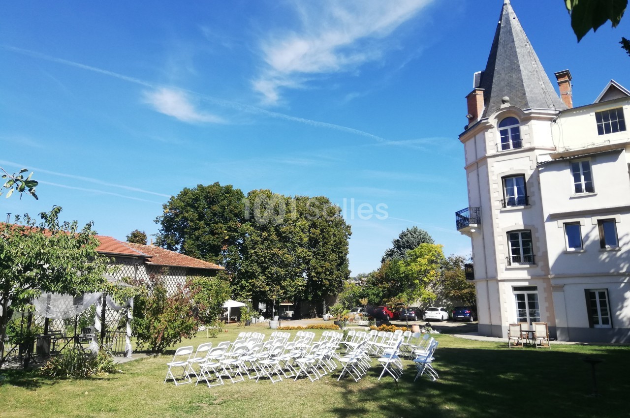 Chaises blanches disposées en extérieur sur une pelouse, près d'un bâtiment ancien sous un ciel bleu.