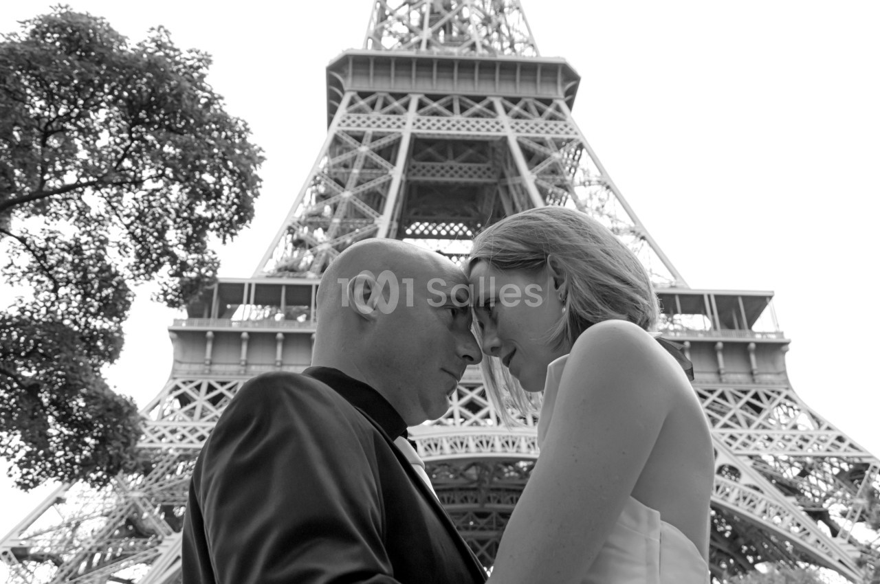 Un couple se regarde tendrement devant la tour Eiffel en noir et blanc.